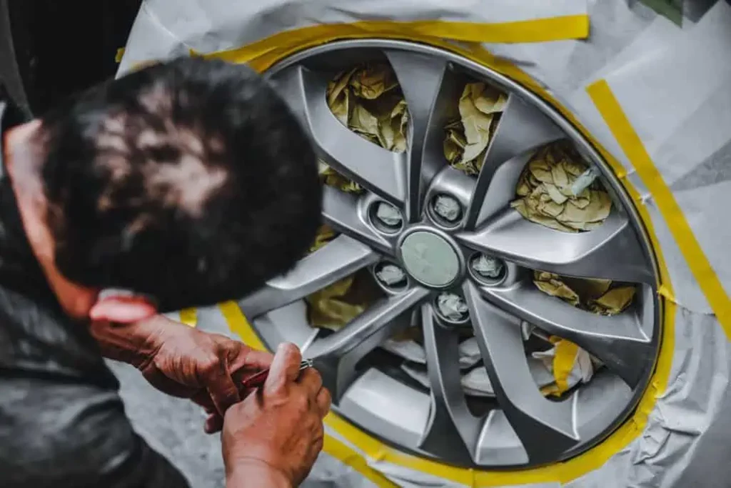 Student airbrushing an alloy wheel for repair.